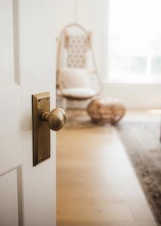 an open door with a handle on it in a living room next to a rocking chair