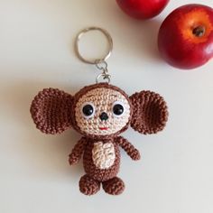 a crocheted monkey keychain sitting next to an apple