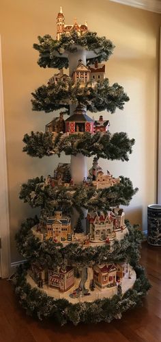 a christmas tree is decorated with lights and houses in the shape of townhouses on top