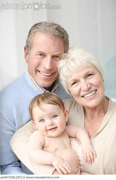 an older man and woman holding a baby