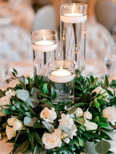 candles and flowers are arranged on the centerpiece for this elegant table setting at a wedding reception