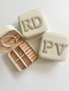 three white jewelry boxes with personalized items in them on top of a table next to each other