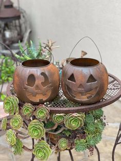 two pumpkin shaped pots sitting on top of a metal stand