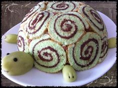 there is a cake that looks like a turtle on top of some rolls and two small green turtles