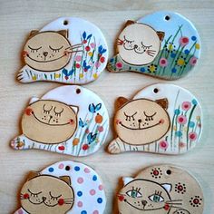 six ceramic tags with cartoon cats and flowers on them, all decorated in different colors