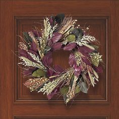 a wreath with dried flowers and leaves is hanging on the front door, ready to be hung