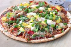 a pizza topped with lots of toppings on top of a wooden table next to a bottle opener