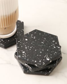 black marble coasters with white speckles and a vase on the table behind them