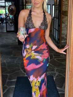 a woman in a colorful dress is holding a wine glass and posing for the camera