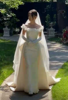 a woman in a wedding dress is walking down the sidewalk