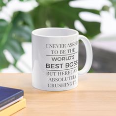 a white coffee mug sitting on top of a wooden table next to a blue book