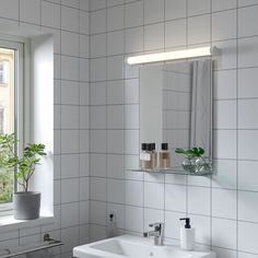 a bathroom with a sink, mirror and plants in the window sill next to it