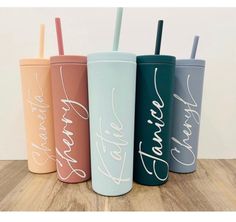 four different colored tumblers with names on the side and straws in each one