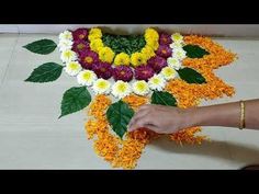 the person is making a flower arrangement on the floor with flowers and leaves around it