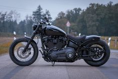 a black motorcycle is parked on the side of the road in front of some trees