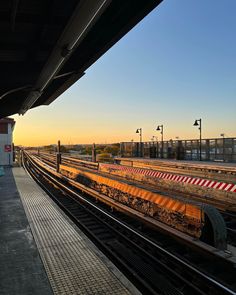 an empty train station with the sun setting