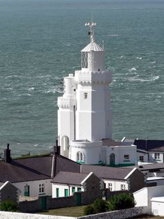 a large white tower with a clock on it's side next to the ocean