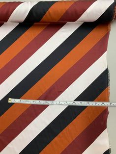 an orange, black and white striped fabric with a measuring tape