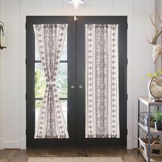 the front door is decorated with black and white curtains, along with deer antlers