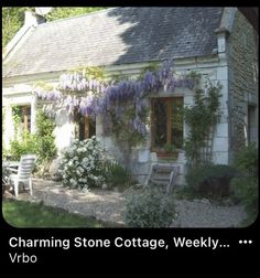 a stone cottage with wistery vines growing over it