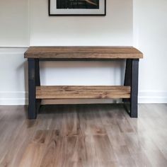 a wooden table sitting on top of a hard wood floor next to a white wall