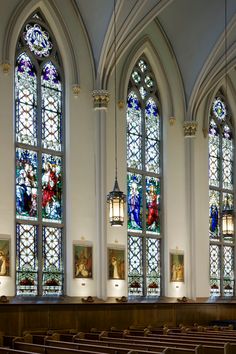 the interior of a church with stained glass windows, pews and lights hanging from the ceiling