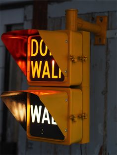 two yellow traffic lights with do or don't walk signs on them