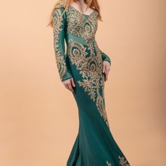 a woman in a long green dress with gold embroidery on the shoulders and neckline