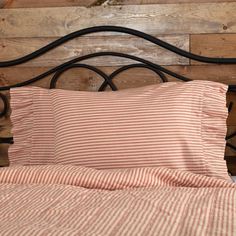 a bed with red and white striped sheets, pillows and headboard made out of wood planks