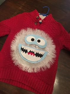 a red sweater with a monster face on it