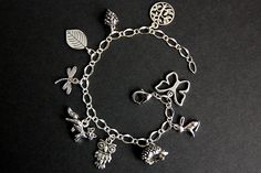 A collection of silver plated crochet themed charms have been dispersed around a shimmering silver plated bracelet chain in this handmade charm bracelet. This crochet charm bracelet is then completed with a lobster clasp and a 1/2 inch of chain at the end for adjustable sizing. Charms in this bracelet include a tree charm, pinecone charm, leaf charm, dragonfly charm, fox charm, owl charm, porcupine charm, rabbit charm, and butterfly charm. ● Sizing ● To determine your bracelet size, do a snug me Whimsical Silver Charms For Gifts, Bohemian Silver Personalized Bracelets, Whimsical Silver Dangling Charms, Dainty Silver Charm Bracelet With Dangling Charms, Whimsical Nickel Free Charm Bracelet Gift, Whimsical Nickel-free Charm Bracelet Gift, Silver Charm Bracelet With Vintage Charm As A Gift, Handmade Silver Metal Charms, Cute Handmade Silver Jewelry