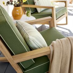 two green chairs sitting on top of a wooden floor next to a vase with flowers