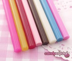 four different colored candles sitting on top of a pink and white checkered table cloth