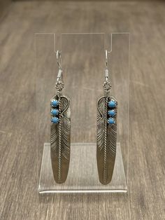 Add a touch of Native American flair to your jewelry collection with these stunning handmade Kingman turquoise dangle earrings. Crafted by Navajo artisan Chester Charley , these earrings are made of high-quality sterling silver and feature beautiful blue stones that will complement any outfit. The intricate design of these earrings showcases the expert craftsmanship of Native American jewelry makers. These earrings are perfect for anyone who loves unique, one-of-a-kind pieces that have a rich cultural history. With certification that they are handmade by a Native American artist, you can be assured of their authenticity. These earrings are not just a beautiful accessory, but a piece of art that you'll treasure for years to come. NAVAJO HANDMADE STERLING SILVER KINGMAN TURQUOISE POST EARRIN Artisan Turquoise Nickel-free Earrings, Southwestern Style Dangle Jewelry As Gift, Artisan Nickel-free Turquoise Earrings, Nickel Free Southwestern Dangle Jewelry, Handmade Southwestern Drop Earrings, Southwestern Turquoise Jewelry With Ear Wire, Southwestern Turquoise Drop Earrings, Turquoise Nickel-free Southwestern Earrings, Nickel-free Turquoise Southwestern Earrings