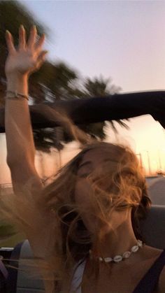 a woman is waving out the window of a car with her hands in the air