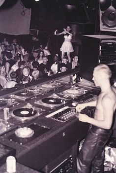 a man standing in front of a dj's turntables at a party