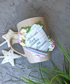 a coffee cup with some writing on it next to a plant and starfish decorations