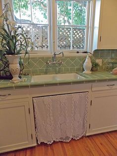 a kitchen with green tile counter tops and white cabinets