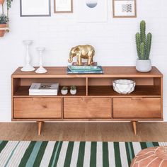 a living room with an elephant figurine on top of a book shelf next to a cactus