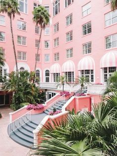 a pink building with palm trees and stairs