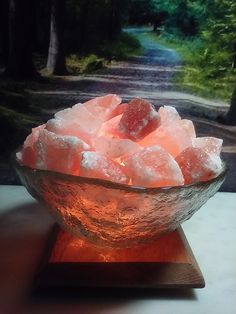 a glass bowl filled with sugar on top of a wooden table next to a forest