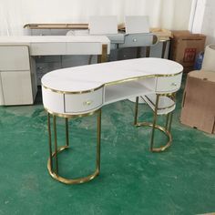 a white desk with gold trim on it in a room filled with boxes and other furniture