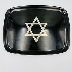 a black and gold tray with a star of david on the front inlayed to it