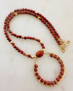 This statement necklace is on-trend and can serve as a layering necklace or hold its own by itself. Beautiful Red Jasper stones are highlighted by non-tarnish gold plated pewter faceted beads and a decorative non-tarnish gold plated pewter hook and eye clasp. Natural Gemstone Necklace. Red Jasper beads are 4mm round faceted round. Red Jasper is associated with grounding, stability, vitality, protection, emotional stability, passion, and spiritual alignment. Throughout history, turquoise has been Beaded Jasper Round Beads Jewelry, Beaded Jasper Jewelry, Beaded Jasper Jewelry With Round Beads, Handmade Jasper Round Beads Necklaces, Gift Jasper Beaded Necklaces, Spiritual Beaded Jasper Necklaces, Elegant Beaded Jasper Necklaces, Elegant Jasper Beaded Necklaces, Artisan Wire Wrapped Necklace For Jewelry Making