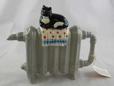 a ceramic cat sitting on top of a radiator