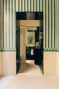 an open door leading to a bathroom with green and white wallpaper