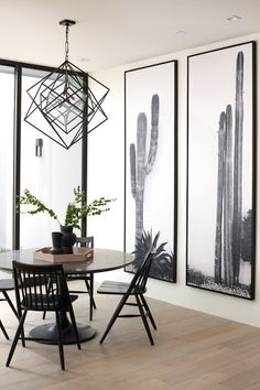 a dining room table with four chairs in front of two large cactus pictures on the wall