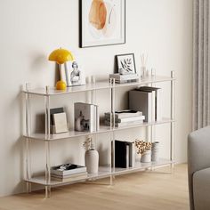 a white shelf with books and pictures on it in a living room next to a couch