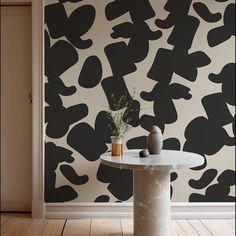 a table with two vases on it in front of a black and white wall