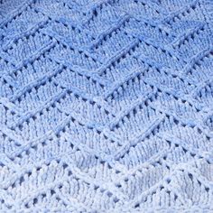 a crocheted blanket is shown in light blue and has wavy lines on it